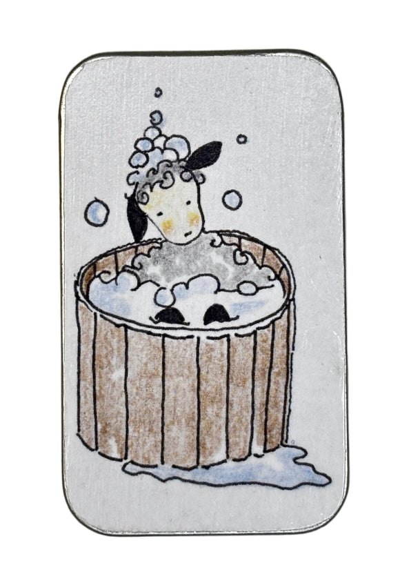 Small rectangular tin with a cartoon design of a sheep in a wooden bathtub on a white background