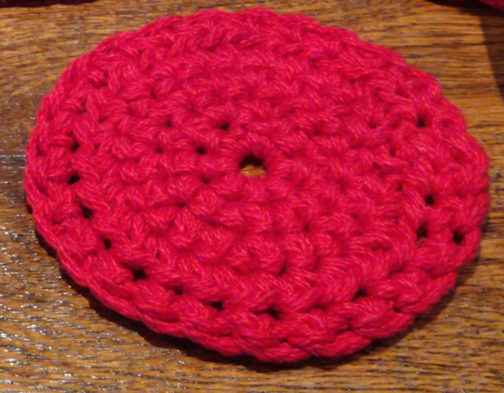 A circular crocheted, red coaster