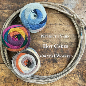 Three balls of the Plymouth Yarn Hot Cakes sitting within a lasso laying on a wooden surface