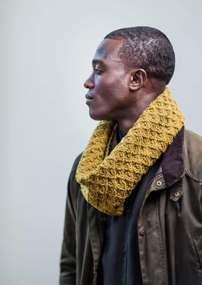 A man wearing a cabled, knitted cowl
