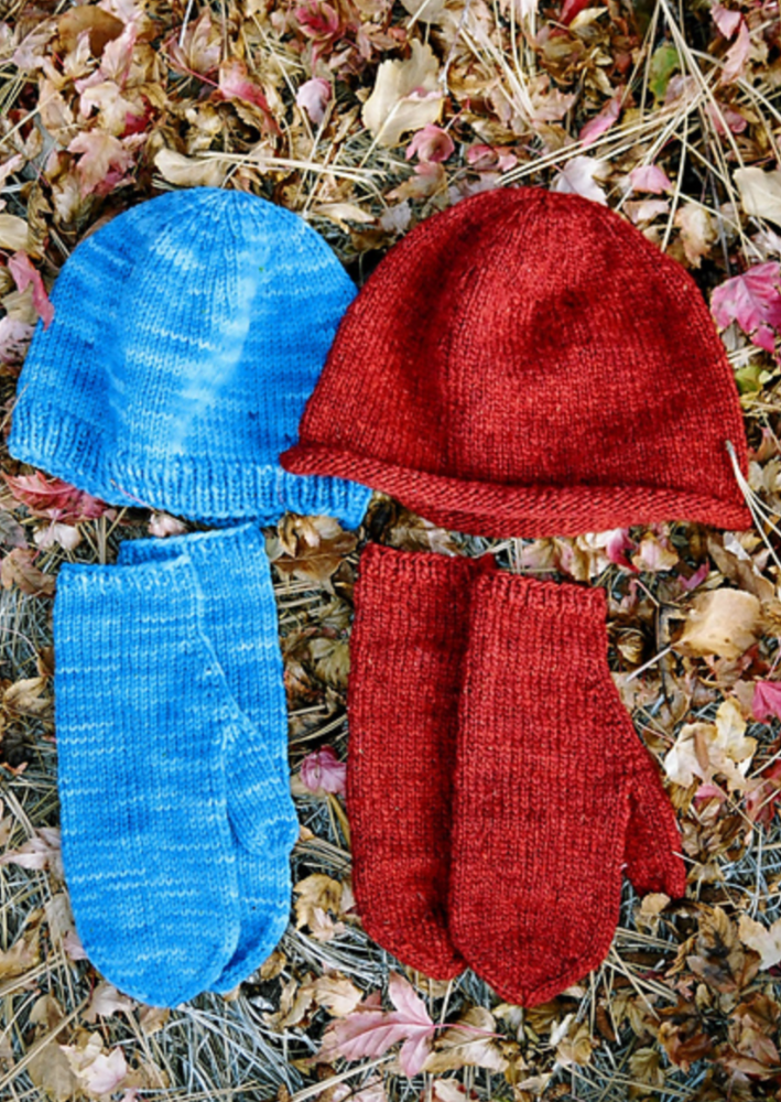 Two knitted hats and mittens on the grass