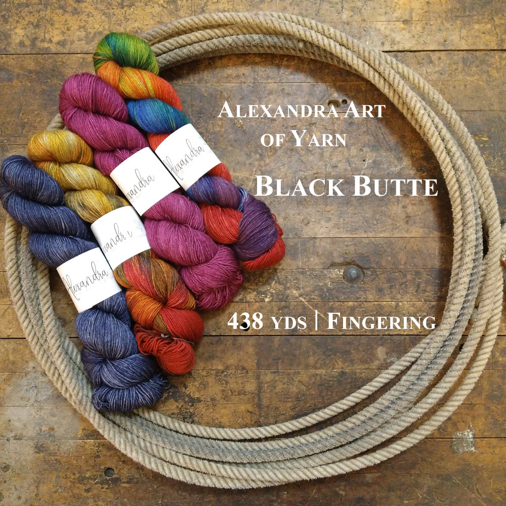 Photo of four colorful hanks of Black Butte yarn in a lasso on a wooden surface