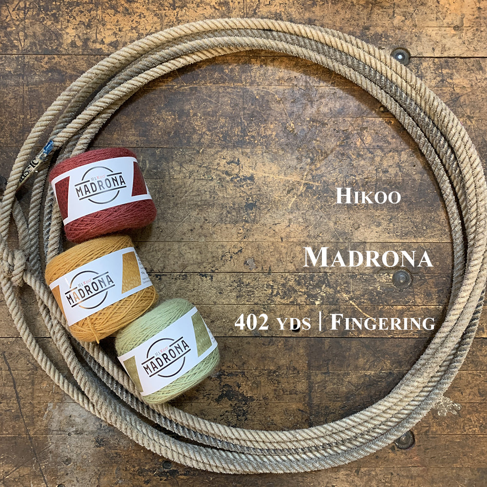 Photo of three balls of HiKoo Madrona yarn in a lasso on a wooden surface