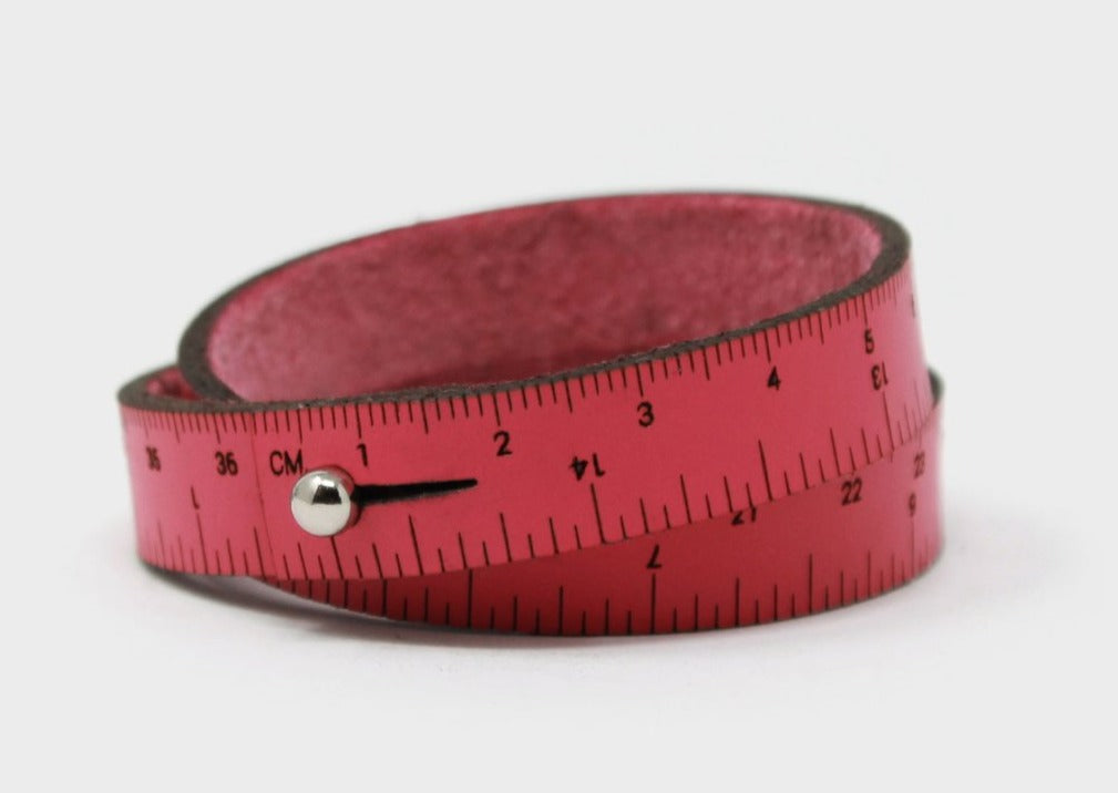 A photo of a hot pink wrist ruler with engraved measurements
