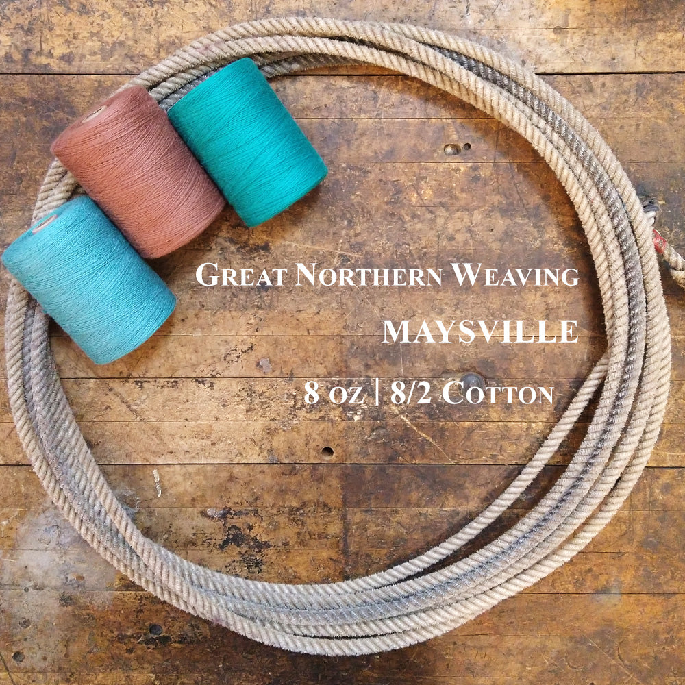 Three colorful tubes of Maysville 8-2 cotton in a lasso on a wooden surface