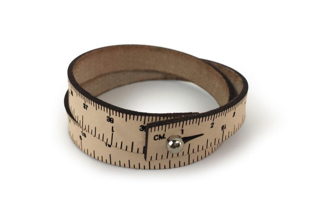 A photo of a tan wrist ruler with engraved measurements