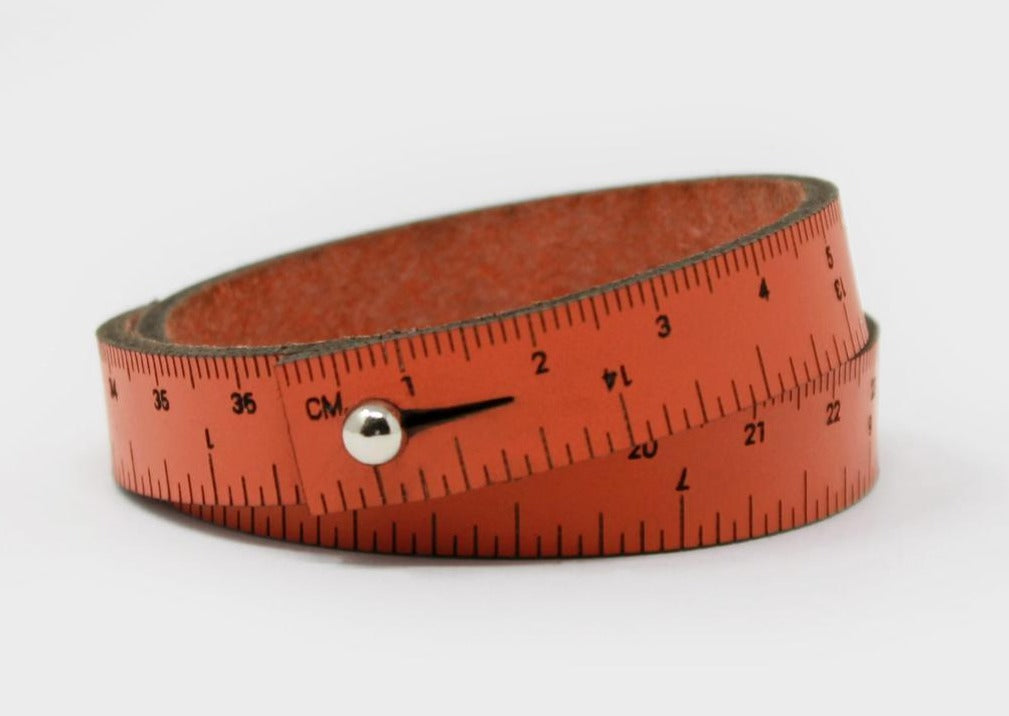 A photo of an orange wrist ruler with engraved measurements