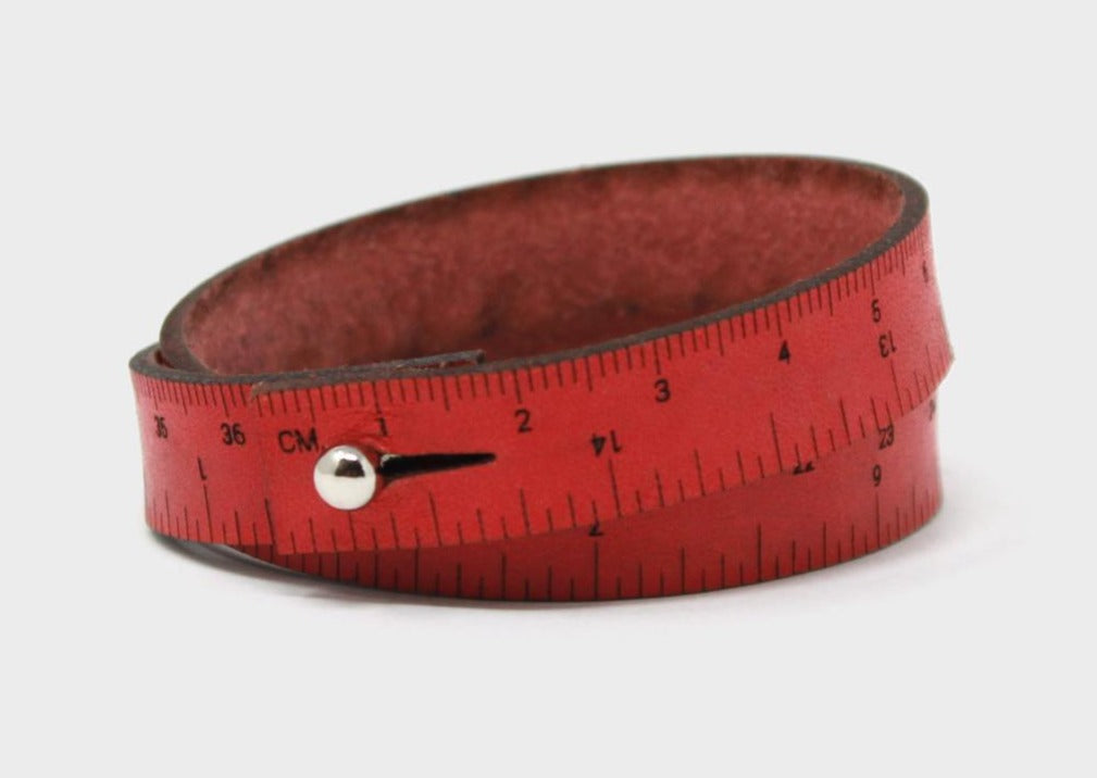 A photo of a burnt orange wrist ruler with engraved measurements
