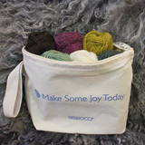 Lanas Light mini skeins of yarn inside a zipper pouch in front of a wool pelt