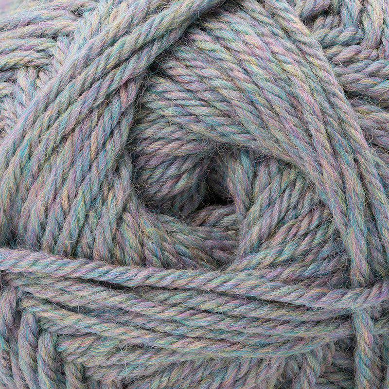 A close-up of twisted yarn wound into a skein, showing a variegated color mix of dusty blue, sage green, lavender, and soft pink.