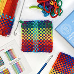 Colorful woven potholder with loom kit components on a white background