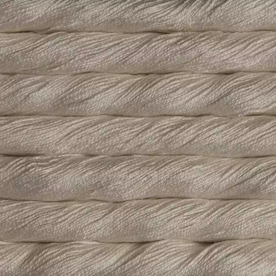 A close-up texture shot of thick, twisted cotton cord or rope in a warm off-white or cream color, stacked horizontally.