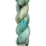 A skein of hand-dyed fingering/sock yarn color white tan teal navy black speckles