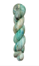 A skein of hand-dyed fingering/sock yarn color white tan teal navy black speckles