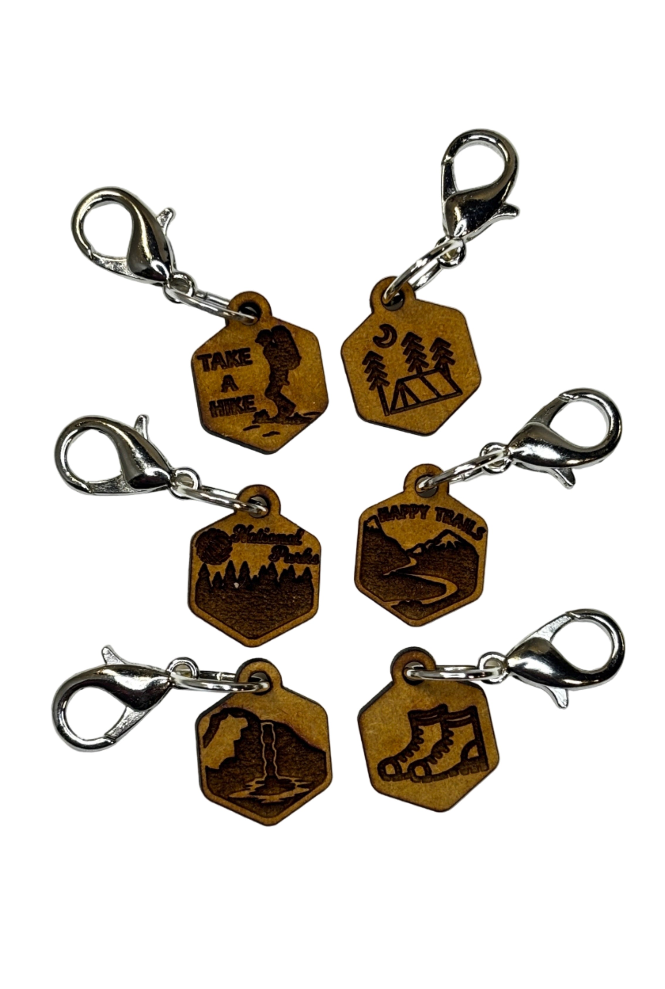 Wooden stitch markers with engraved detail of hiking boots, a tent, waterfall and other outdoors type things