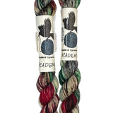 Two mini skeins of wool yarn hand dyed in Wyoming in the color brown red green black