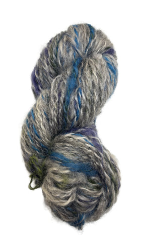 Skein of multicolored handspun yarn in the colors grey blue purple green
