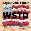 Colorful yarn skeins with 'American Fiber' and 'Mitchell Wool Co.' branding on a wooden background.