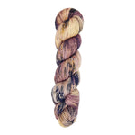 A skein of hand-dyed fingering/sock yarn color mauve off white purple navy black speckles