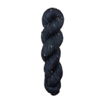 Dark black skein of yarn with white specks on a white background