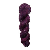 Purple skein of yarn with black and white specks on a white background