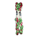 Two skeins of red, green, and white yarn on a white background