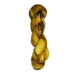 Skein of hand dyed fingering weight yarn in the color yellow tan brown red orange speckles