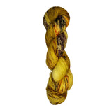 Skein of hand dyed fingering weight yarn in the color yellow tan brown red orange speckles