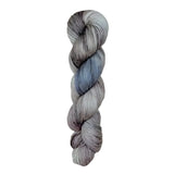 A skein of hand-dyed fingering/sock yarn color grey blue black speckles
