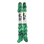 Two mini skeins of wool yarn hand dyed in Wyoming in the color green and black streaks