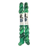 Two mini skeins of wool yarn hand dyed in Wyoming in the color green and black streaks