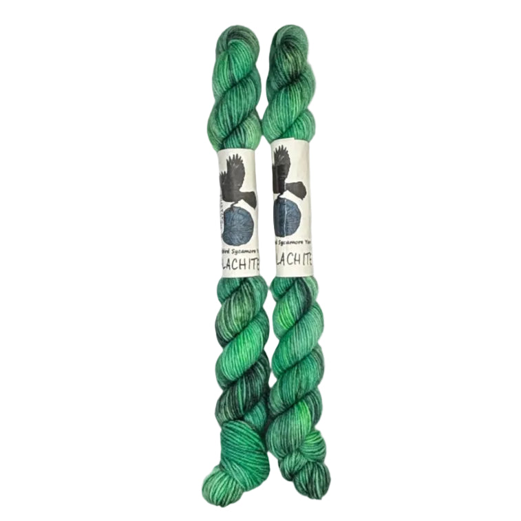 Two mini skeins of wool yarn hand dyed in Wyoming in the color green and black streaks