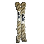 Two mini skeins of  off white yarn on a white background 