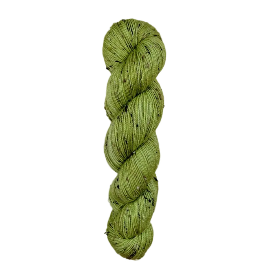Green skein of yarn with black speckles on a white background