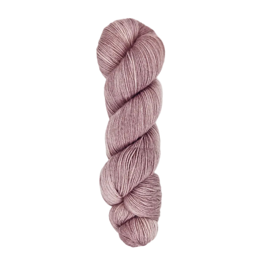 A skein of hand-dyed fingering/sock yarn color dusty pink