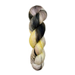 A skein of hand-dyed fingering/sock yarn color grey yellow peach mauve black
