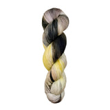 A skein of hand-dyed fingering/sock yarn color grey yellow peach mauve black