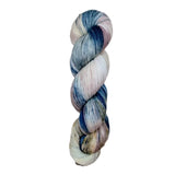 A skein of hand-dyed fingering/sock yarn color pink white blue brown speckles