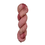 A skein of hand-dyed fingering/sock yarn color pink red brown speckles