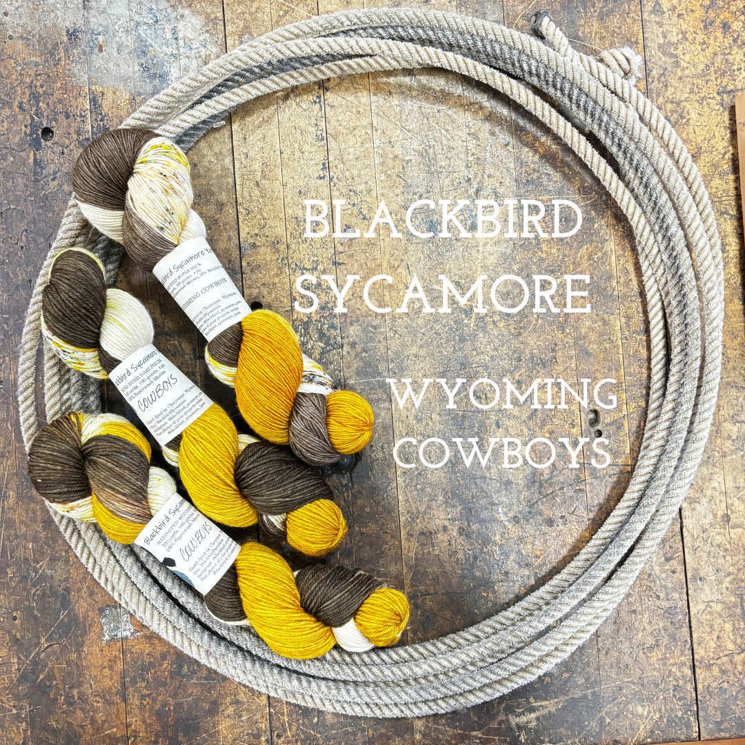 Skeins of hand dyed wool yarn in uw brown and gold colors on a wooden surface