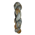 Skein of hand dyed fingering weight yarn in the color grey orange black speckles