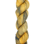 A skein of hand-dyed fingering/sock yarn color yellow tan navy black speckles