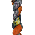 A skein of hand-dyed fingering/sock yarn color grey orange yellow dark green speckles