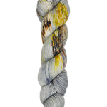 A skein of hand-dyed fingering/sock yarn color grey yellow orange brown speckles
