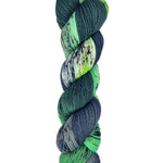 A skein of hand-dyed fingering/sock yarn color green white grey black speckles