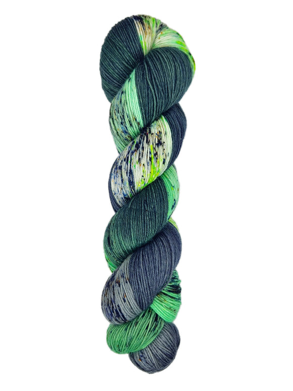A skein of hand-dyed fingering/sock yarn color green white grey black speckles