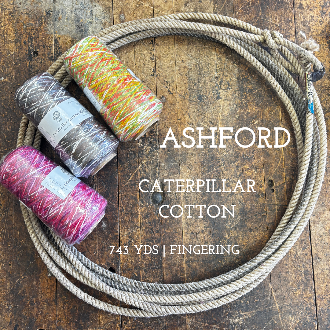 Cones of multi-colored cotton weaving yarn on a wooden surface