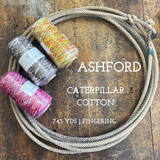 Cones of multi-colored cotton weaving yarn on a wooden surface