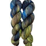 A skein of hand-dyed fingering/sock yarn color green brown blue grey black speckles