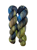 A skein of hand-dyed fingering/sock yarn color green brown blue grey black speckles